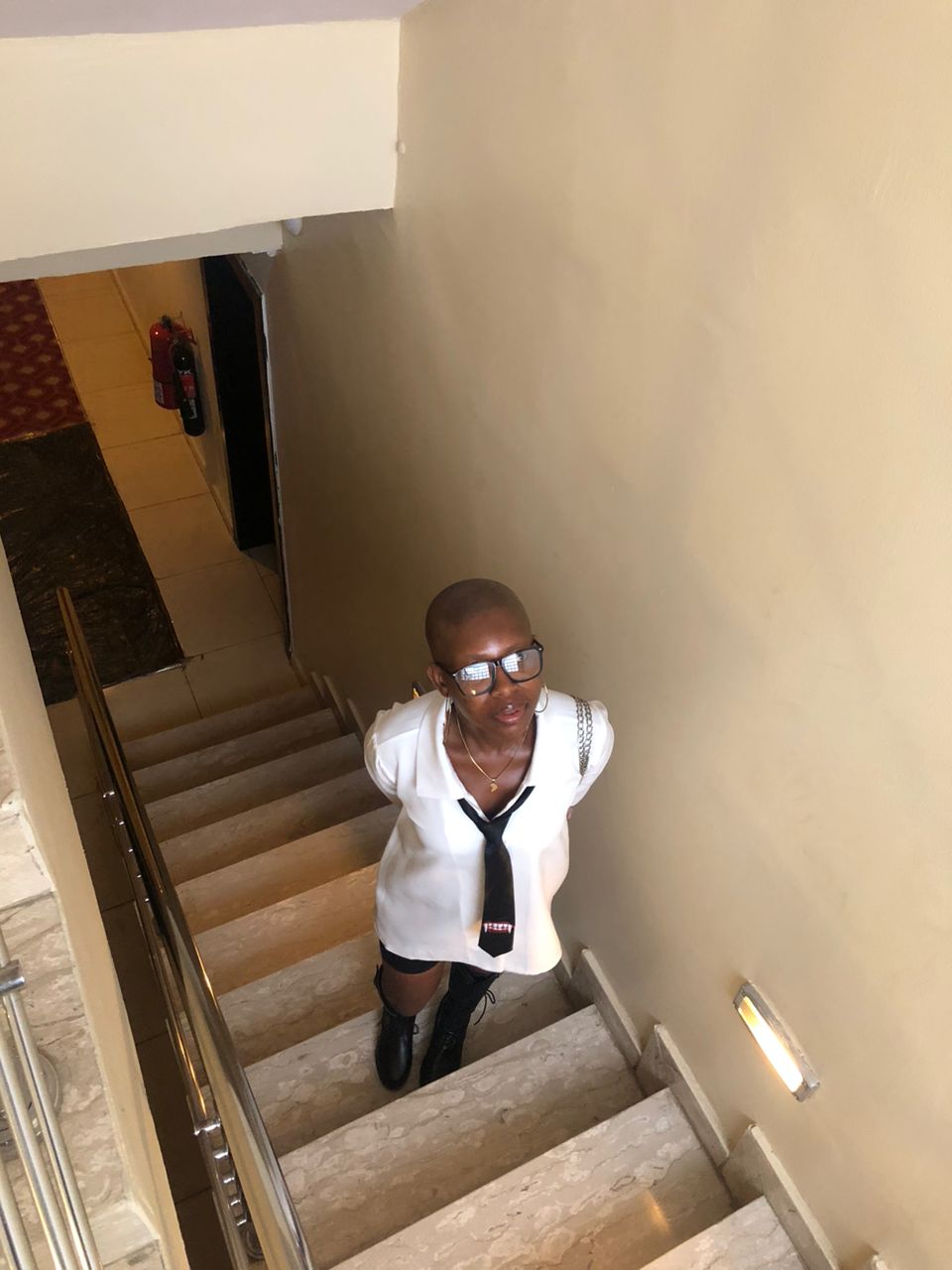Adora looking strtaight at the camera wearing black clothes, glasses and fabulous jewelry