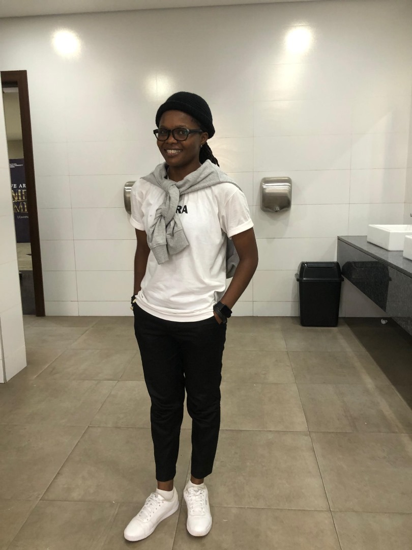 Adora looking strtaight at the camera wearing black clothes, glasses and fabulous jewelry